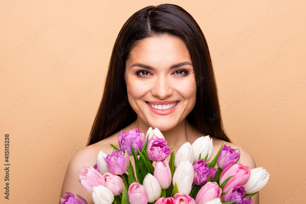 Photo of charming nice pretty happy woman hold flowers flawless skin isolated on beige color background Photo of charming nice pretty happy woman hold flowers flawless skin isolated on beige color background
