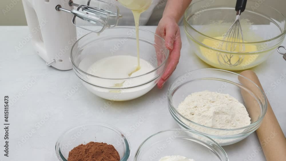Close up baking process. Chef adds condensed milk into a bowl with whisked egg whites. Step by step chocolate cake recipe Close up baking process. Chef adds condensed milk into a bowl with whisked egg whites. Step by step chocolate cake recipe
