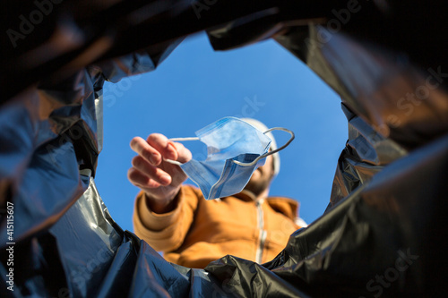 Point of view shot of man throwing away surgical mask in trash can