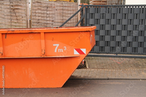 an old orange construction waste container on the street 