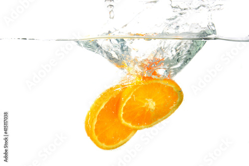 whole orange and tangerine and sliced slices falls under water