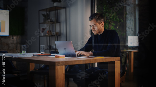 Handsome Caucasian Male is Working on Laptop Computer while Sitting Behind a Conference Table in Meeting Room in an Creative Agency. Project Manager is Busy With Business Strategy and Development.