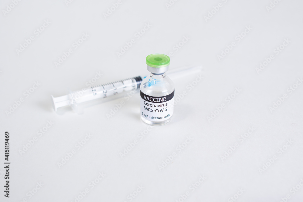 Coronavirus Covid-19 vaccine concept - one glass vial on white table. Syringe for injection on background Coronavirus Covid-19 vaccine concept - one glass vial on white table. Syringe for injection on background