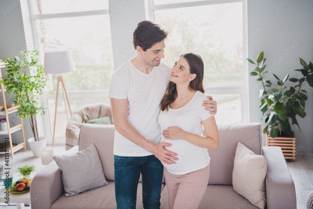 Photo of good mood positive family waiting baby hugging tummy looking each other sofa indoors inside Photo of good mood positive family waiting baby hugging tummy looking each other sofa indoors inside