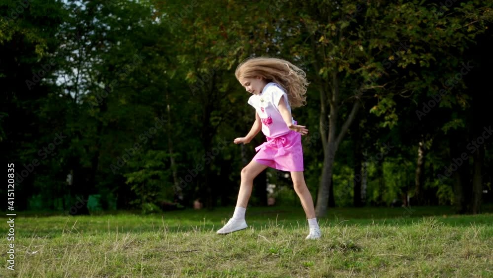 Little girl having fun on the green grass while making an acrobatic wheel. Young sporty kid has a really good mood. Little girl having fun on the green grass while making an acrobatic wheel. Young sporty kid has a really good mood.