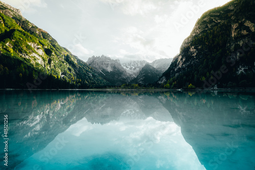 Landscape of the Durrensee lake surrounded by rocky hills under a cloudy sky and sunlight in Italy photo