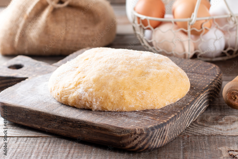 Raw dough on a cutting board on a rustic wooden table. Frozen dough