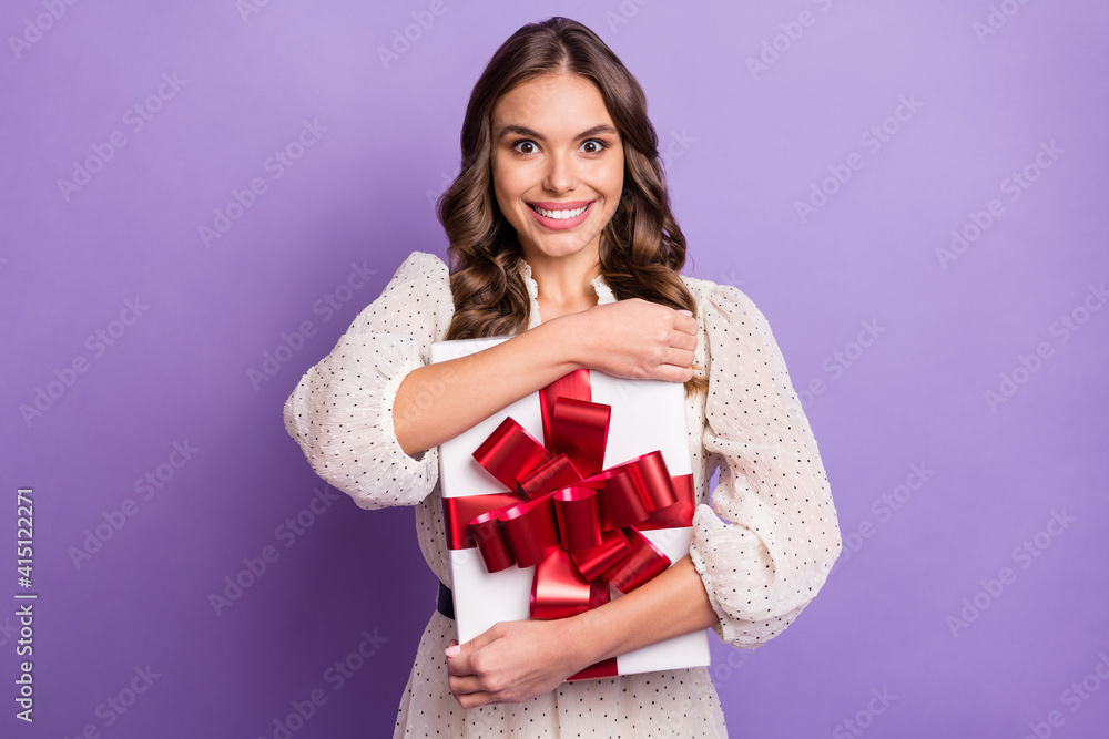 Photo portrait of excited model keeping festive gift box in white pointed dress smiling isolated on pastel purple color background Photo portrait of excited model keeping festive gift box in white pointed dress smiling isolated on pastel purple color background
