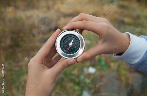 Woman hands with magnetic compass in mountains.