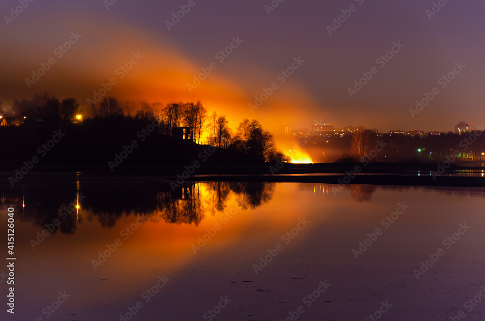 dry grass is burning. natural fire. reflection in water