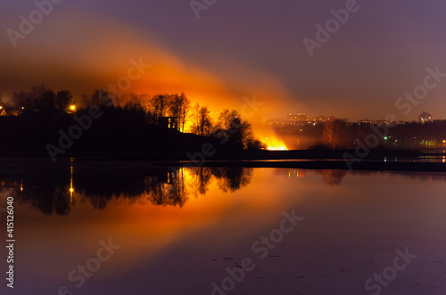 dry grass is burning. natural fire. reflection in water © Oleg