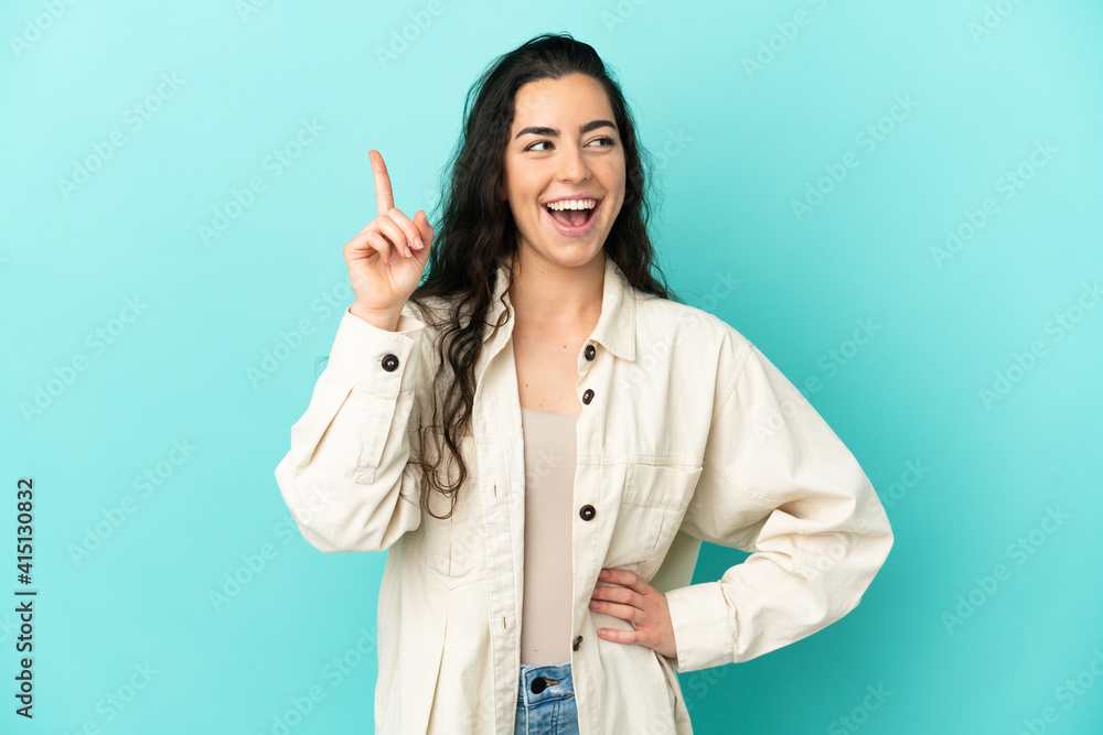Young caucasian woman isolated on blue background intending to realizes the solution while lifting a finger up Young caucasian woman isolated on blue background intending to realizes the solution while lifting a finger up