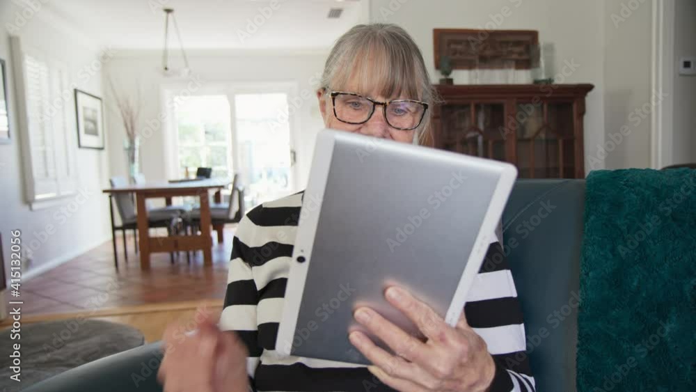 Happy Senior Caucasian woman using tablet computer while sitting in living room. Older white lady using app on e-reader to check news or browse the internet. Slow motion 4k Happy Senior Caucasian woman using tablet computer while sitting in living room. Older white lady using app on e-reader to check news or browse the internet. Slow motion 4k