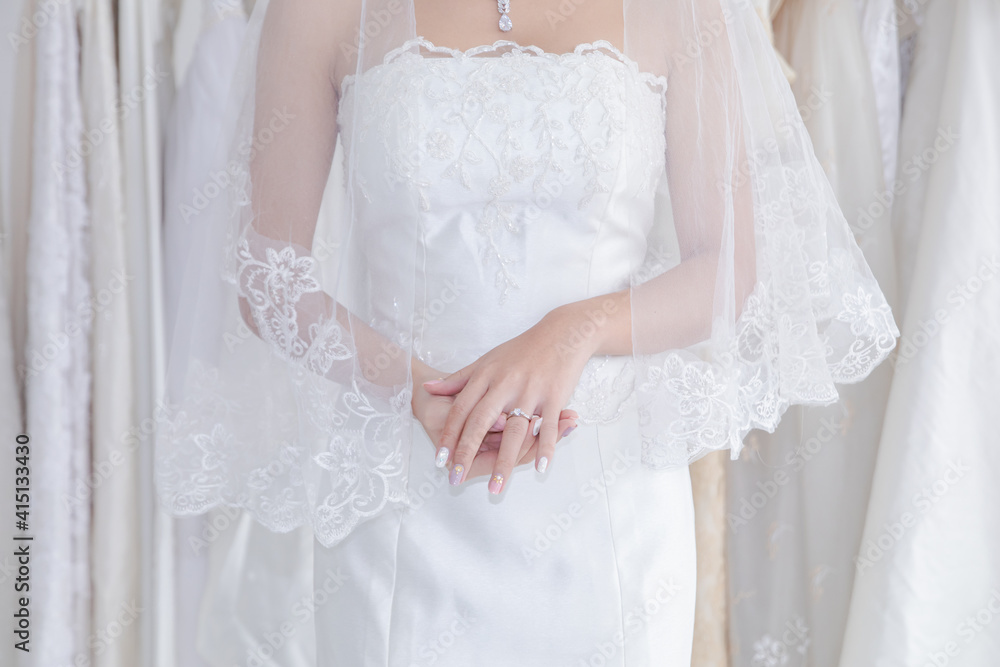 Beautiful Asian bride happy post to camera while dress up elegant wedding lace dress, wedding dress maker try to fit the bride suit in wedding studio or Wedding dress shop store Beautiful Asian bride happy post to camera while dress up elegant wedding lace dress, wedding dress maker try to fit the bride suit in wedding studio or Wedding dress shop store