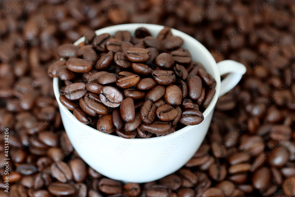 Fototapeta premium Coffee beans in white cup. Dark and roasted, concept of natural drink