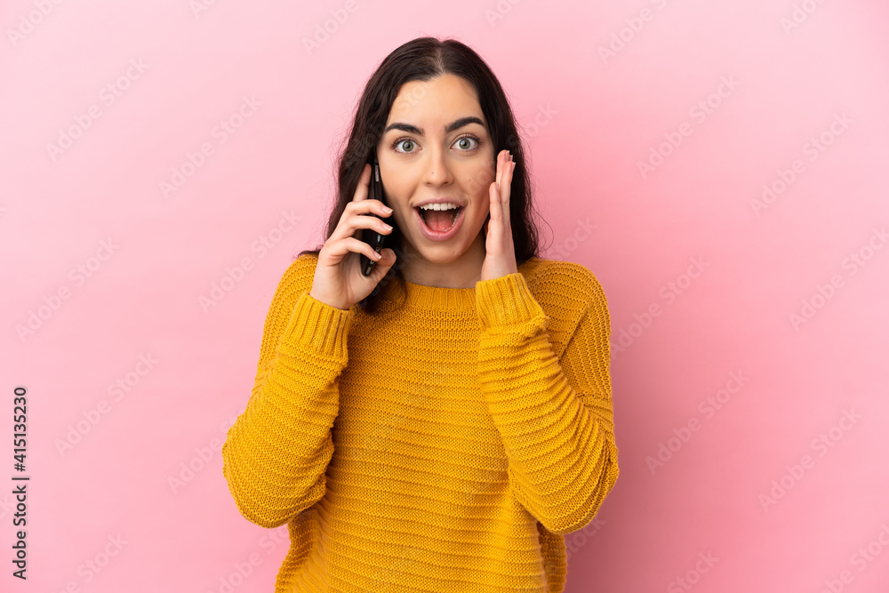 Young caucasian woman using mobile phone isolated on pink background with surprise and shocked facial expression Young caucasian woman using mobile phone isolated on pink background with surprise and shocked facial expression