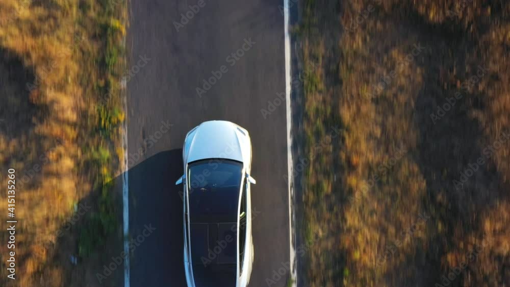 Aerial shot of electrical car driving on country road at summer evening. New SUV vehicle speeding through highway. Ecology friendly car riding on electric charge along motorway. Top view Close up