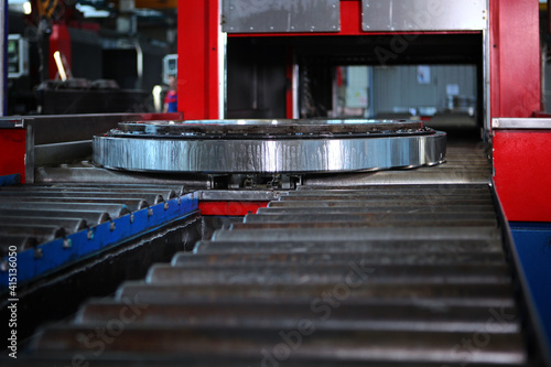 The finished large diameter bearing is coated with oil before packaging and storage. Metal products. Conveyor in the production of bearings. Out of focus. Engine oil. photo