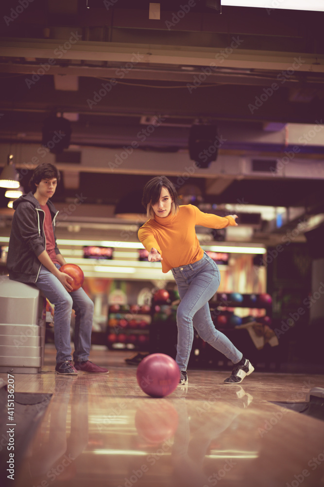 Couple in blowing  alley. Woman throws a bowling ball.