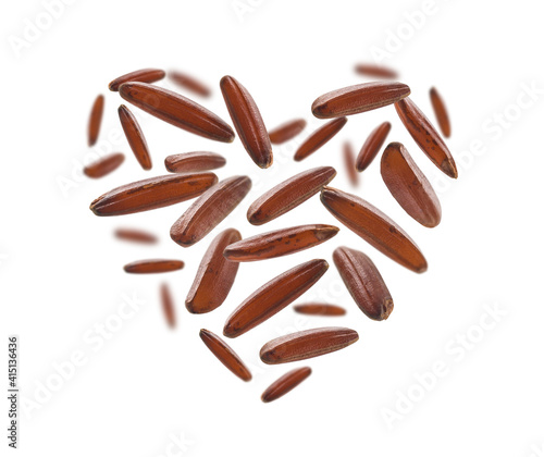 Raw brown rice in the shape of a heart on a white background