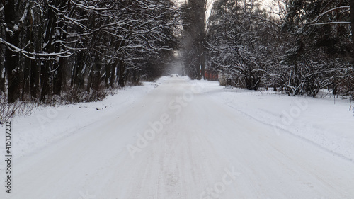 Winter landscape. Snow-covered trail in the city park. Snow covered trees in a winter forest with a road.