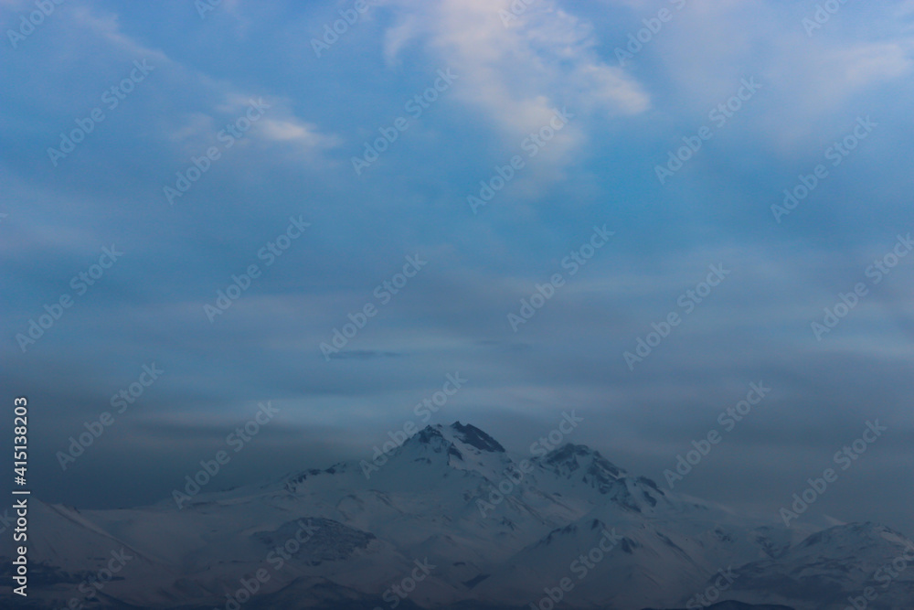 Snowy view of Mount Erciyes in Kayseri, Turkey. Cityscape with mountain and clouds in the evening.