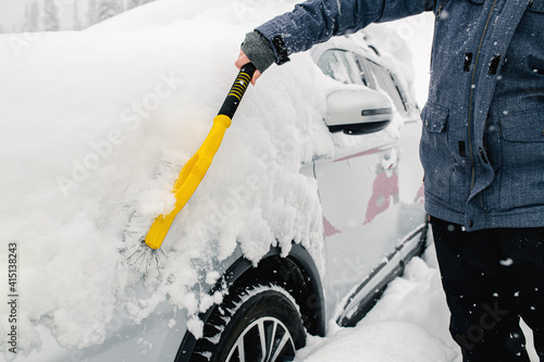 Man cleaning his car from a snow.