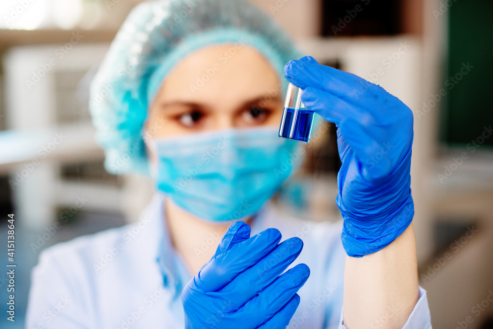 The student prepares a solution for a lesson in chemistry or biotechnology. A girl holding a blue solution The student prepares a solution for a lesson in chemistry or biotechnology. A girl holding a blue solution