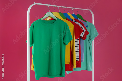 Rack with stylish children clothes on pink background © New Africa