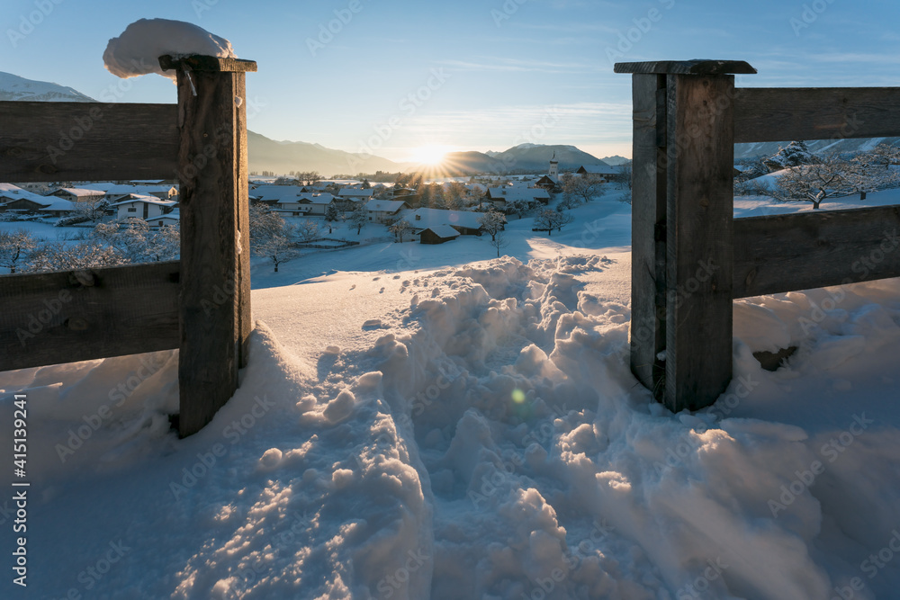 Snow covered rural winter landscape seen through fence during sunset, Wildermieming, Tirol, Austria Snow covered rural winter landscape seen through fence during sunset, Wildermieming, Tirol, Austria