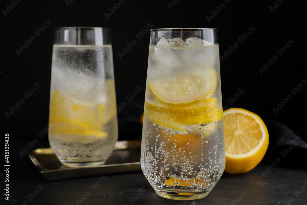 Soda water with lemon slices and ice cubes on black table Soda water with lemon slices and ice cubes on black table