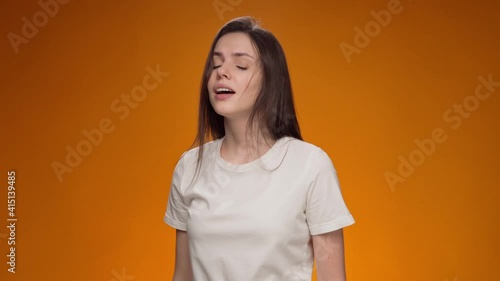 Young sick woman sneezing into elbow against yellow background photo