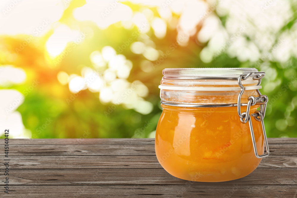 Jar of orange jam on wooden table against blurred background, space for text Jar of orange jam on wooden table against blurred background, space for text