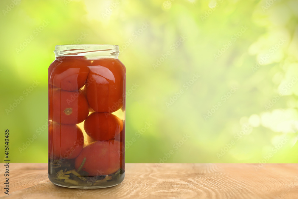 Jar of pickled tomatoes on wooden table against blurred background, space for text Jar of pickled tomatoes on wooden table against blurred background, space for text