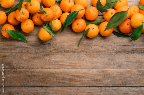 Fresh ripe tangerines with green leaves on wooden table, flat lay. Space for text