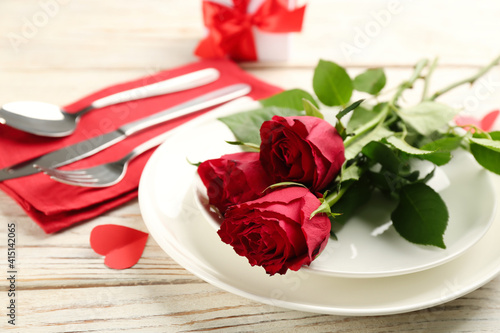 Beautiful table setting for Valentine s Day dinner with roses on white wooden background  closeup