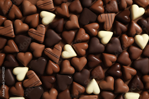 Beautiful heart shaped chocolate candies on brown background, flat lay