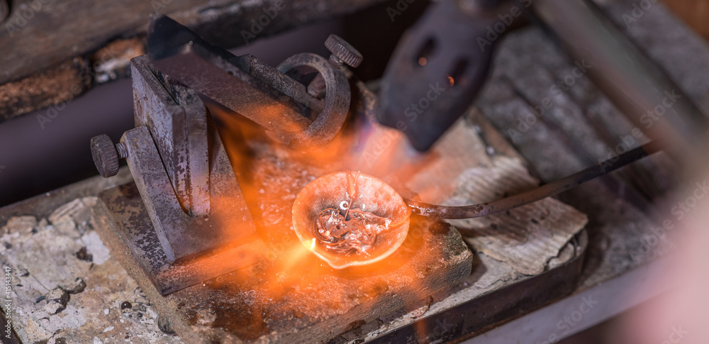 Melting process of precious metal gold behind a jeweler's workbench Melting process of precious metal gold behind a jeweler's workbench