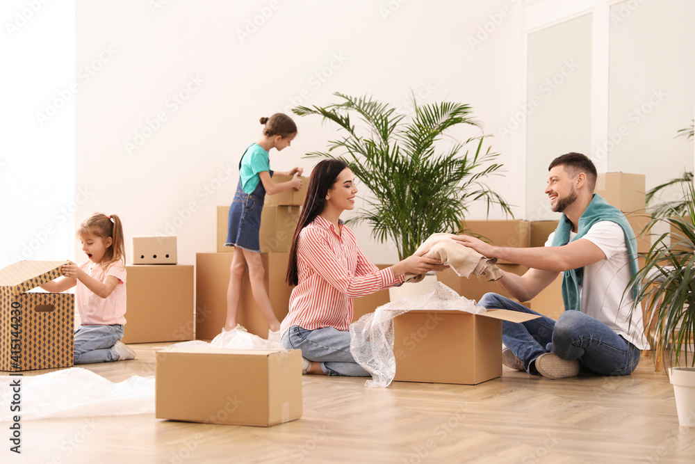 Happy family unpacking moving boxes in new house Happy family unpacking moving boxes in new house