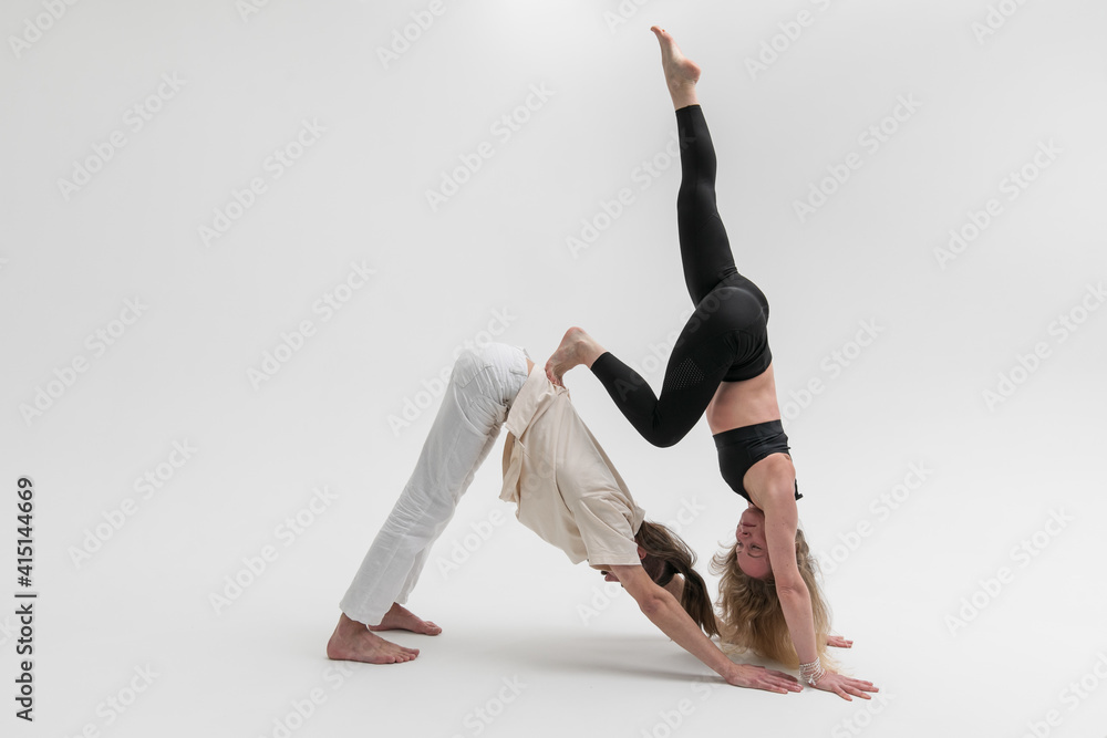 Couple of young people practicing contact yoga in studio on white background. А man and a woman lean on each other during psychological therapeutic exercise Couple of young people practicing contact yoga in studio on white background. А man and a woman lean on each other during psychological therapeutic exercise