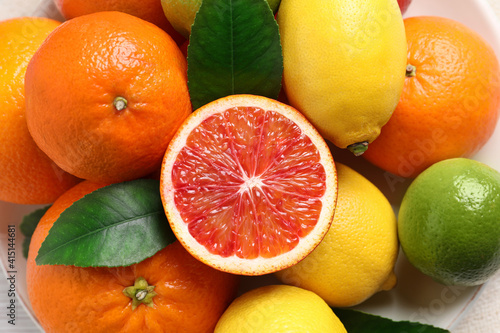Different ripe citrus fruits on plate, closeup