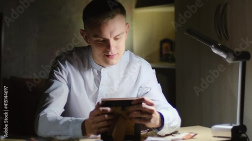 Nostalgia, memories concept. Young guy holding a framed photo in his hands and clutching it to his chest