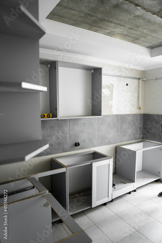 Wallpaper Mural Custom kitchen cabinets installation without a furniture facades mdf. Gray modular kitchen from chipboard material on a various stages of installation in kitchen with a grey tile on floor and walls. Torontodigital.ca