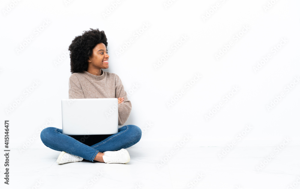 Young African American woman with a laptop sitting on the floor in lateral position Young African American woman with a laptop sitting on the floor in lateral position