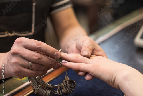 Canvas Print The hands of the jeweler who put the finger ring on the client's hand