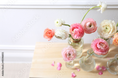 Beautiful ranunculus flowers on table near wall, above view. Space for text