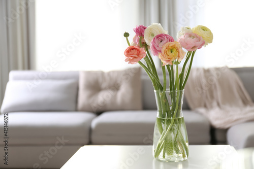 Beautiful ranunculus flowers on table in living room, space for text