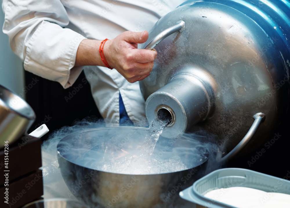 Fototapeta premium Chef is pouring liquid nitrogen from a large Dewar vessel, toned