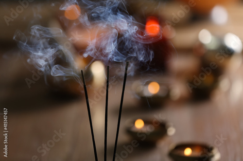 Incense sticks smoldering on blurred background, closeup