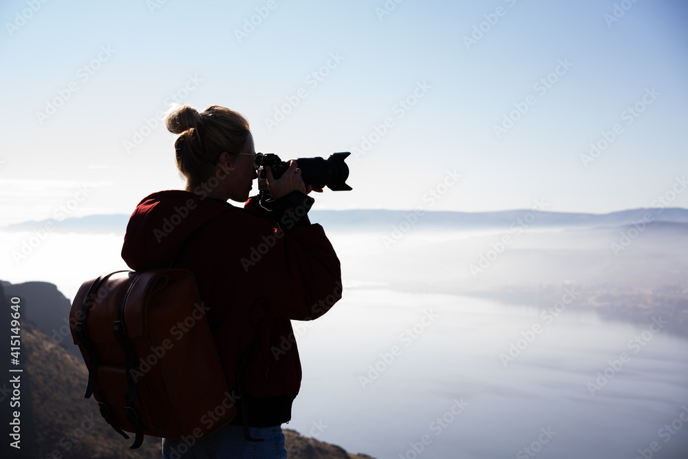 Female photographer shooting view of foggy river with high shores